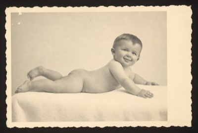 Front shows a baby lying on its stomach on a blanket, smiling. The child was approximately 10 months old when the photograph was taken.