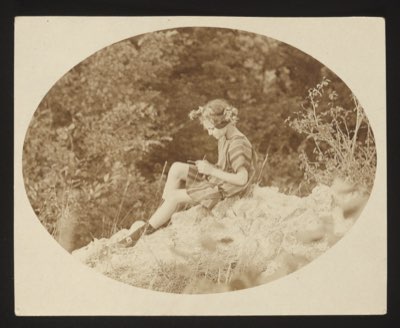 Front shows a young woman sitting on a rock outdoors, reading or writing, in an oval-framed photograph. She is identified as 